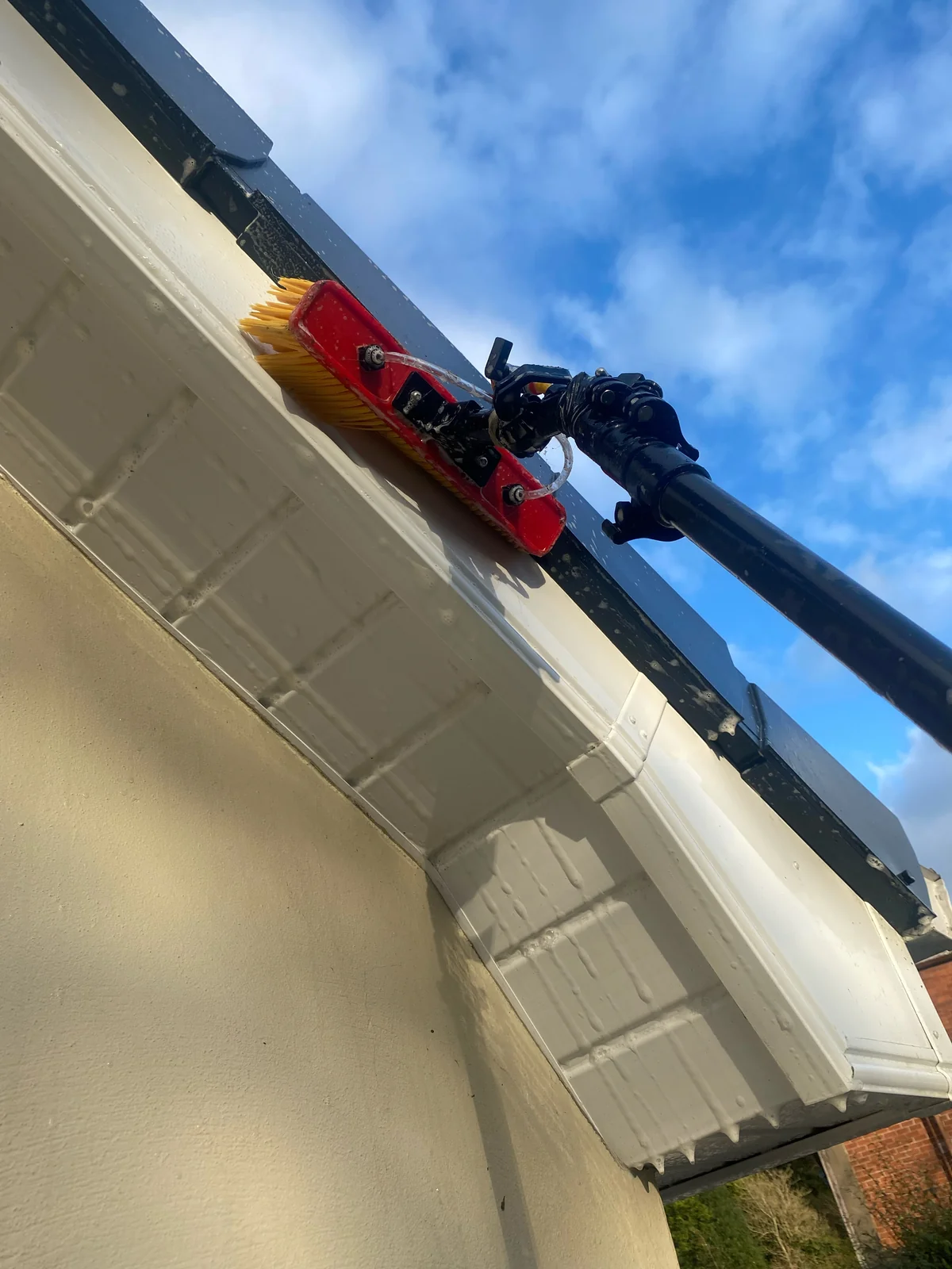 Brush cleaning a fascia and soffit at roofline level
